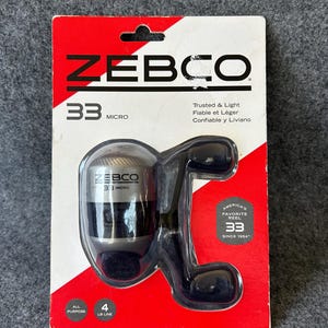 May include: A Zebco 33 Micro fishing reel in its original red and white retail packaging. The reel is silver and black with a dual-handle design. The packaging features the text Zebco 33 Micro, Trusted & Light, and America's Favorite Reel Since 1954.