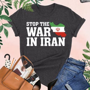 May include: Dark grey heather t-shirt with the text "STOP THE WAR IN IRAN" in white. The shirt features a graphic of the Iranian flag within the country's map. The shirt is paired with blue jeans and a brown tote bag.