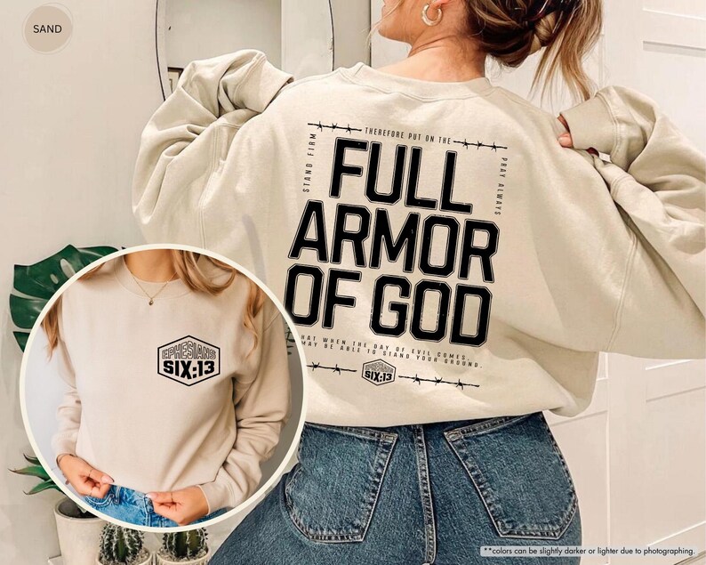 May include: Sand-colored sweatshirt with the text "FULL ARMOR OF GOD" in black on the back. The front of the sweatshirt features a smaller design with the text "SIX:13". The sweatshirt has long sleeves and a crew neck.