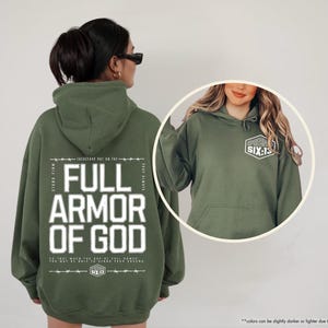 May include: Military green hoodie with the text "FULL ARMOR OF GOD" in white block letters. The back of the hoodie features additional text and the logo "SIX:13". The front of the hoodie has the "SIX:13" logo on the upper left chest.