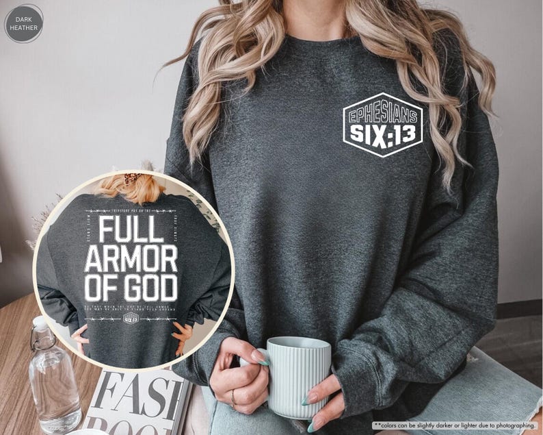 May include: Dark heather gray sweatshirt with the text "Ephesians Six:13" in a white hexagon on the chest. The back of the sweatshirt features the text "Full Armor of God" in a white rectangular design. A casual, comfortable style.