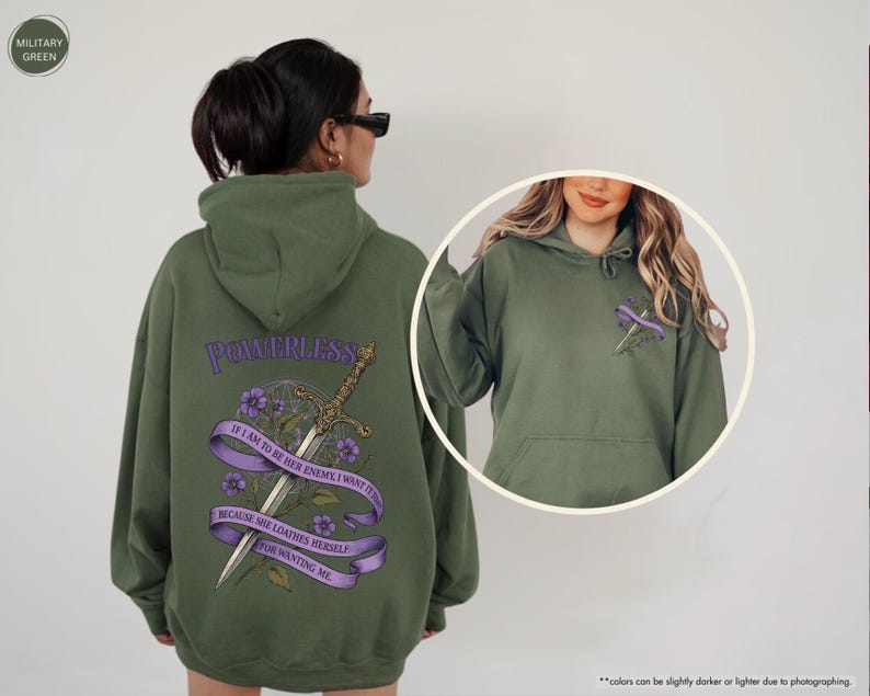 Puede incluir: Una sudadera con capucha verde oliva con la palabra "POWERLESS" sobre una espada y un dise&ntilde;o floral. El texto de la sudadera con capucha dice: "IF I AM TO BE HER ENEMY I WANT IT TO BE BECAUSE SHE LOATHES HERSELF FOR WANTING ME."