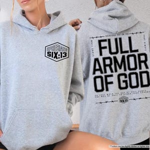 May include: Sport grey hoodie with the text "EPHESIANS SIX:13" on the front and "FULL ARMOR OF GOD" on the back. The hoodie has a drawstring hood and a front pocket. The text is in black.