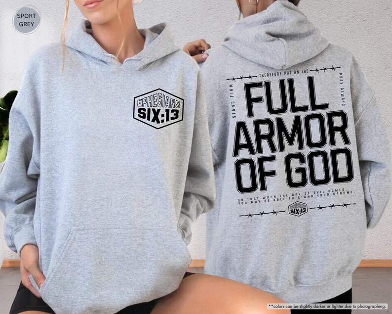 May include: Sport grey hoodie with the text "EPHESIANS SIX:13" on the front and "FULL ARMOR OF GOD" on the back. The hoodie has a drawstring hood and a front pocket. The text is in black.