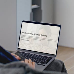 Può includere: Un computer portatile con il testo "Problem Solving & Critical Thinking" sullo schermo. Lo schermo mostra testo e una grafica. Il computer portatile è aperto e la tastiera è visibile. Le mani di una persona sono sulla tastiera.