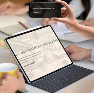 May include: A person holding a smartphone and a tablet. The smartphone displays the text "Innovative Thinking for Everyday Life." The tablet shows the text "Innovative Thinking at Work & in Leader." A yellow mug is visible.