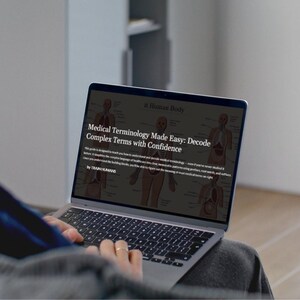 Peut inclure: Un ordinateur portable affiche le texte "Medical Terminology Made Easy: Decode Complex Terms with Confidence" et des illustrations anatomiques. L'ordinateur portable est ouvert, et les mains de l'utilisateur sont visibles sur le clavier.