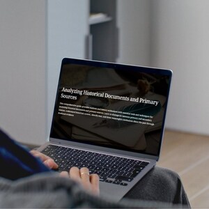 Peut inclure: Un ordinateur portable argenté affiche le texte "Analyzing Historical Documents and Primary Sources". L'écran montre du texte sur l'analyse historique. L'ordinateur portable est ouvert, et la personne porte un pull gris.