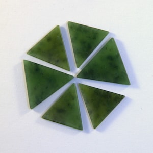 May include: Six green triangular jade stones arranged in a circular pattern on a white background.