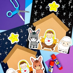 May include: A craft scene featuring a nativity set with stickers of a baby, donkey, sheep, and star. The scene includes a brown house, blue scissors, and glue sticks, set against blue, purple, and black paper.