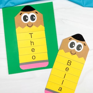 Op de afbeelding: Twee papieren potloodknutsels met cartoongezichten, zwarte punten, houtkleurige secties en gele lichamen. Eén potlood toont de naam Theo op een groene achtergrond, terwijl de andere de naam Bella toont, beide met roze gummen aan de onderkant.