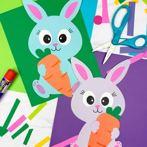 Può includere: Due lavoretti di coniglietti di carta colorata, uno azzurro e uno lavanda, ciascuno con una carota arancione. I coniglietti sono su sfondi verdi e viola, con materiali per lavori manuali come forbici e ritagli di carta.