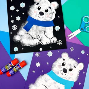 Puede incluir: Dos obras de arte de osos polares hechas a mano. Cada oso es blanco con una bufanda azul, sobre un fondo negro y morado, decorado con recortes de copos de nieve. También se ven barras de pegamento y tijeras.