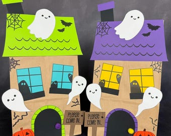 Puede incluir: Dos casas de papel con temática de Halloween con tejados verdes y morados, chimeneas y recortes de fantasmas sonrientes. Cada casa tiene ventanas con siluetas de fantasmas, una calabaza y un letrero que dice "PLEASE COME IN".
