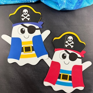 Könnte beinhalten: Zwei Papier-Geister-Ausschnitte als Piraten verkleidet. Jeder Geist trägt einen schwarzen Piratenhut mit weißem Totenkopf, eine Augenklappe und einen Gürtel mit goldener Schnalle. Ein Geist hat eine blaue Weste und gelbe Streifen, der andere eine rote Weste.