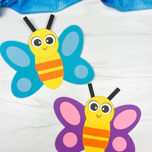 May include: Two colorful paper butterflies. One has blue wings, a yellow body with orange stripes, and black antennae. The other has purple wings with pink accents, a yellow body with orange stripes, and black antennae. The butterflies are on a white surface.