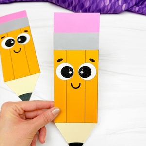 Op de afbeelding: Twee papieren bladwijzers in de vorm van gele potloden met roze gummen, grijze hulzen en zwarte punten. Elke bladwijzer heeft een cartoongezicht met grote zwarte ogen en een glimlachende mond op het gele lichaam.