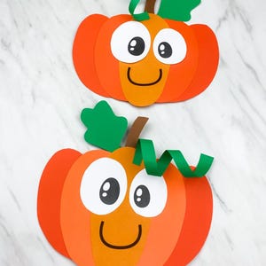 Puede incluir: Dos calabazas de papel naranja y amarillo con caras sonrientes, ojos blancos y hojas verdes. Las calabazas tienen un diseño de dibujos animados, perfecto para decoraciones de otoño o Halloween.