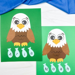 Op de afbeelding: Twee groene papieren knutselprojecten met Amerikaanse zeearenden met witte koppen, bruine lichamen en gele snavels. Onder elke adelaar bevinden zich vier lichtblauwe visvormen, elk bedrukt met een letter die de namen Aria en Noah spelt.
