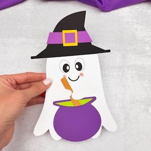 May include: A white paper ghost wearing a black witch hat with a purple band and yellow buckle. The ghost has a smiling face and is holding a spoon over a purple cauldron with green liquid. Halloween-themed craft.