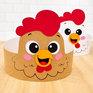 May include: Two chicken-themed paper headbands. One is brown with a red comb, pink cheeks, and a yellow beak. The other is white with a red comb, pink cheeks, and a yellow beak. Both have large black eyes and are smiling. The headbands are on a light wood surface.