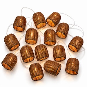 Pode incluir: Uma série de luzes decorativas com pequenas abajures castanhos tecidos. Cada abajur emite um brilho laranja quente. As luzes são presas em um fio transparente e fino, criando um ambiente acolhedor.