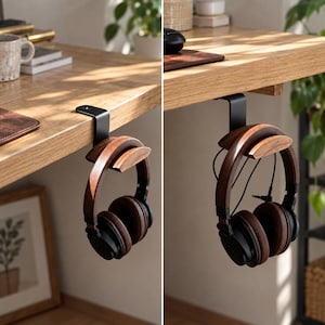 May include: A black metal headphone hanger with a curved wooden support piece, designed to clamp onto the edge of a desk. The hanger holds a pair of over-ear headphones featuring dark wood ear cups and black padding, suspended securely below the surface.