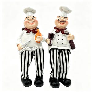 Peut inclure: Deux figurines de chefs portant des toques blanches, des vestes blanches avec des foulards rouges et des pantalons à rayures noires et blanches. Un chef tient un couteau et une baguette, l'autre un verre à vin sombre et une bouteille, en chaussures noires.