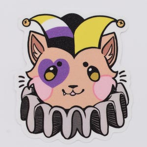 May include: A sticker featuring a cartoon cat with a jester hat in yellow, black, and non-binary colors. The cat has a purple heart-shaped eye patch and a ruffled collar. The cat's face is peach-colored with pink cheeks and a small smile.