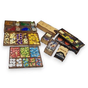 Puede incluir: Organizador de juegos de madera con múltiples compartimentos y bandejas. El organizador contiene varias piezas de juego, incluyendo fichas, cartas y dados. Las piezas son de diferentes colores, como rojo, verde, azul y amarillo. El organizador está diseñado para mantener los componentes del juego organizados.