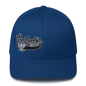 May include: A royal blue baseball cap with a black embroidered logo that says "Von Zombie Original".