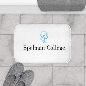 May include: White bath mat with the text "Spelmen College" and a blue silhouette of a woman's head.