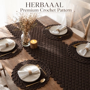 Puede incluir: Una mesa de comedor con un camino de mesa de ganchillo marrón oscuro y manteles individuales a juego. Cada lugar incluye una servilleta blanca, cubiertos dorados y un plato beige. La mesa está decorada con un jarrón de flores secas y una vela encendida. El texto "HERBAAAL Premium Crochet Pattern" está en la parte superior.