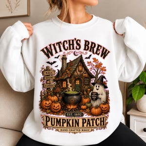 Peut inclure: Un sweat-shirt blanc à col rond avec une impression graphique colorée représentant une maison hantée, un chaudron bouillonnant, des citrouilles et un fantôme portant un chapeau de sorcière. Le texte indique Witch's Brew, Pumpkin Patch et plus.