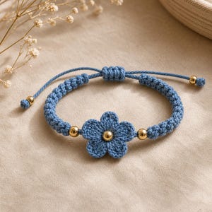 Peut inclure: Bracelet bleu en crochet avec une fleur et des détails dorés. Le bracelet fait main a une fermeture de style macramé et des perles dorées. Un bijou délicat et élégant, parfait pour toutes les occasions.
