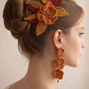May include: A crocheted floral hair accessory and earrings in shades of orange, yellow, and red. The hairpiece features a large flower and leaves, while the earrings dangle with three flower pendants. The handmade set adds a touch of bohemian flair.
