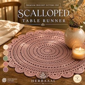 Peut inclure: Nappe ronde en crochet de couleur rose poudré, avec bordure festonnée. Le motif est ajouré et détaillé. Le texte « SCALLOPED TABLE RUNNER » et « HERBAAAL » est visible. Une bougie et un vase avec des fleurs séchées sont également présents.