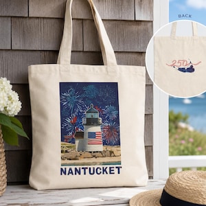 Op de afbeelding: Een crèmekleurige canvas tas met een afbeelding van een vuurtoren met een Amerikaanse vlag, omringd door blauw en rood vuurwerk, met de tekst NANTUCKET eronder. De achterkant van de tas toont het getal 250 in het rood met een kleine afbeelding.