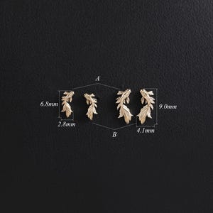 May include: Four gold-toned fish-shaped earrings arranged in two pairs labeled A and B. The smaller pair A measures 6.8mm by 2.8mm, while the larger pair B measures 9.0mm by 4.1mm. Each earring features detailed fins and a textured body design.