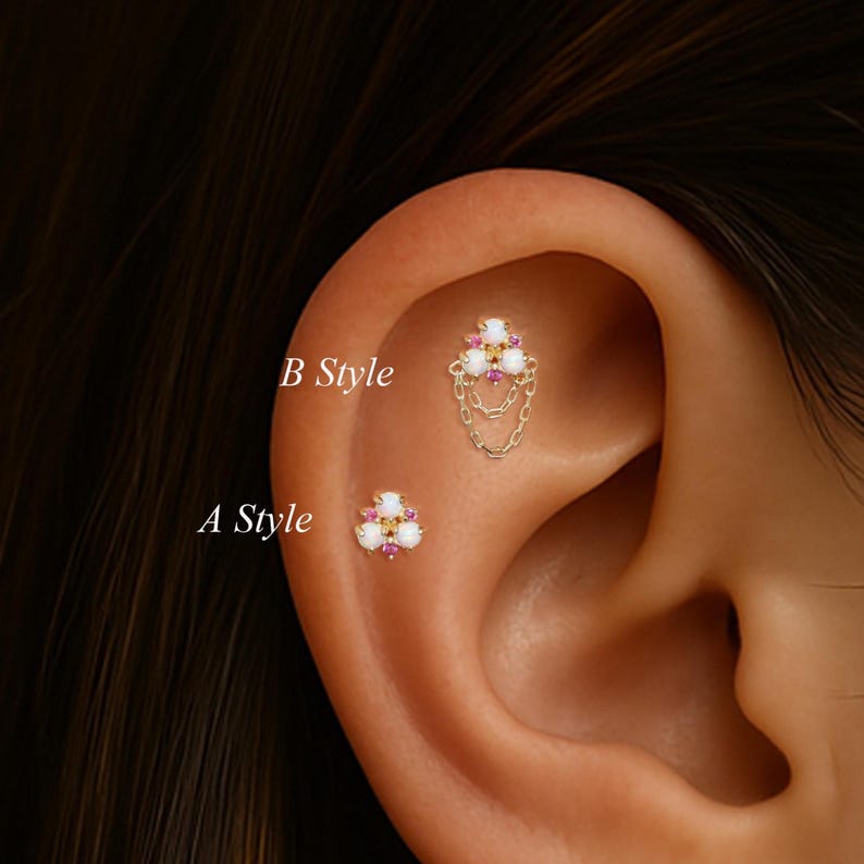 May include: Two gold-toned ear piercings are shown, labeled "A Style" and "B Style". "A Style" is a small stud with white, pink, and yellow stones. "B Style" has a similar design, with dangling chains.