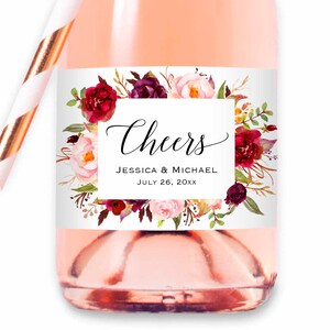 Pu&ograve; includere: Un'etichetta per bomboniere di matrimonio bianca con una ghirlanda floreale bordeaux e rosa. L'etichetta dice "Cheers Jessica & Michael July 26, 20XX".