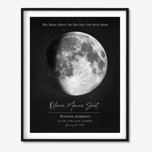 May include: A framed black and white print titled The Moon Above On The Day You Were Born, featuring a detailed lunar image, the name Olivia Maria Scoot, the phase Waxing Gibbous, and birth details: 2:10 am, 6 lbs, 10 oz, 20 inches, January 20, 2024.