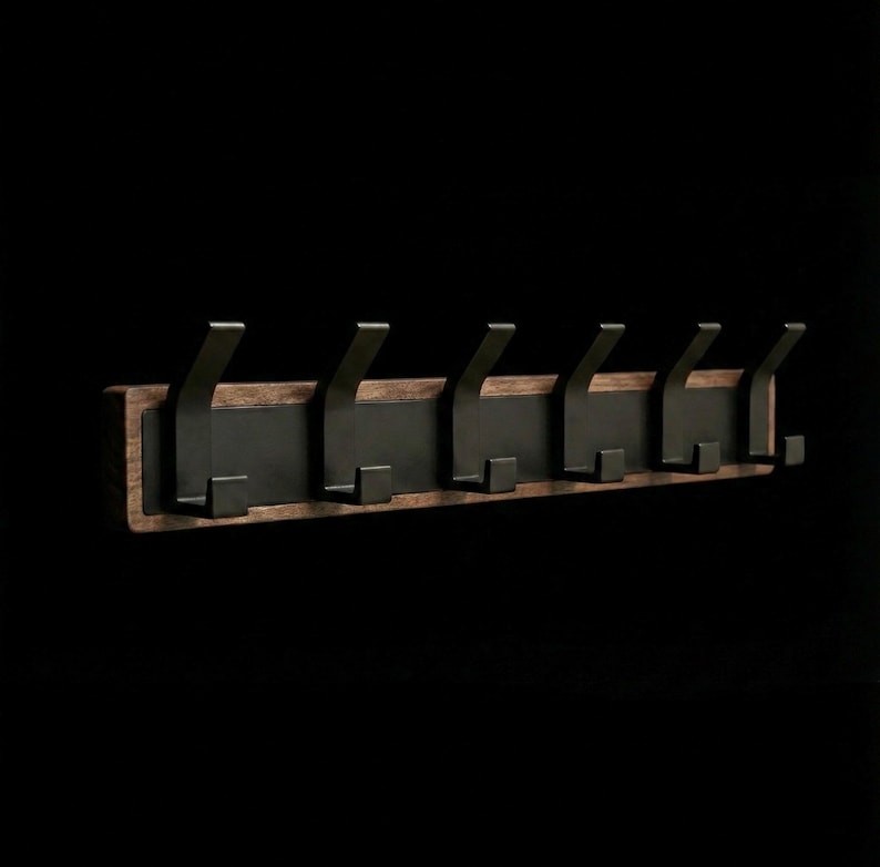 Pu&ograve; includere: Un attaccapanni da parete con sei ganci in metallo nero. I ganci sono montati su una tavola di legno rettangolare con finitura marrone scuro. Lo sfondo &egrave; nero pieno.
