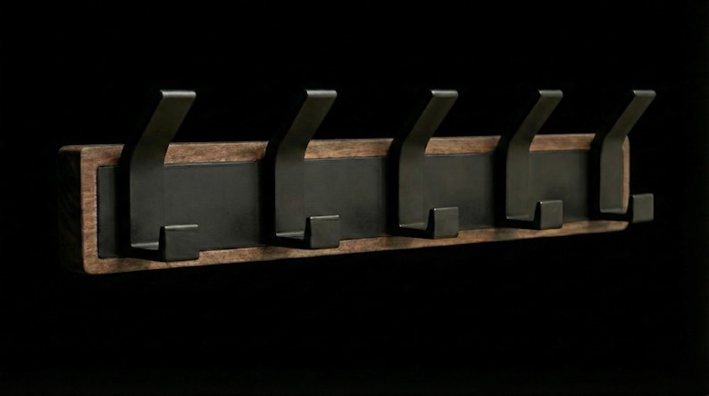 Pu&ograve; includere: Un attaccapanni rustico da parete con cinque ganci in metallo scuro. I ganci sono montati su una tavola rettangolare di legno con un centro marrone scuro e un bordo in legno pi&ugrave; chiaro. Design semplice e moderno.