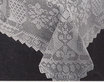 May include: A white crocheted tablecloth with a delicate floral pattern. The tablecloth is laid out on a table with plates, glasses, and silverware.