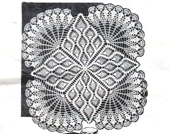 May include: A white crocheted doily with a peacock feather design. The doily is displayed on top of a television set.
