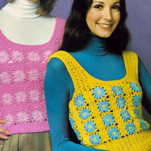 May include: Two women wearing crocheted sleeveless tops. The woman on the left is wearing a pink top with a white turtleneck underneath. The woman on the right is wearing a yellow top with a blue turtleneck underneath.