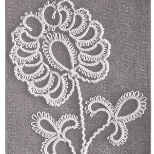 May include: A white crocheted flower with a stem and leaves. The flower has a delicate, intricate design.