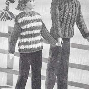 May include: A black and white striped sweater with long sleeves and a white hat with a black and white striped pattern. The sweater is paired with black pants. A second person is wearing a brown sweater with a turtleneck and black pants.