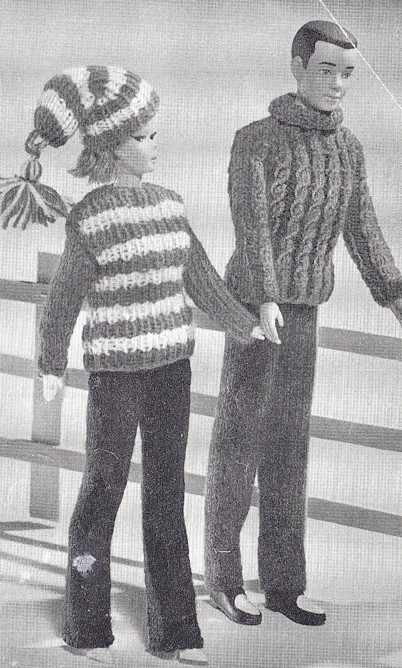 May include: A black and white striped sweater with long sleeves and a white hat with a black and white striped pattern. The sweater is paired with black pants. A second person is wearing a brown sweater with a turtleneck and black pants.